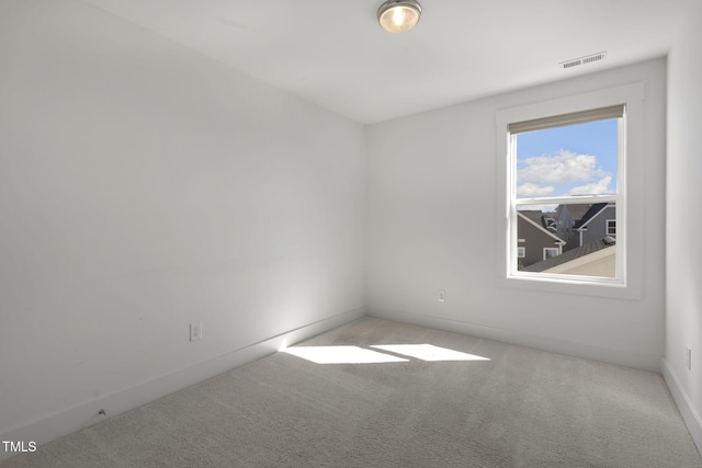 carpeted empty room featuring baseboards and visible vents