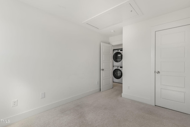 laundry room featuring laundry area, stacked washer / dryer, carpet, and baseboards