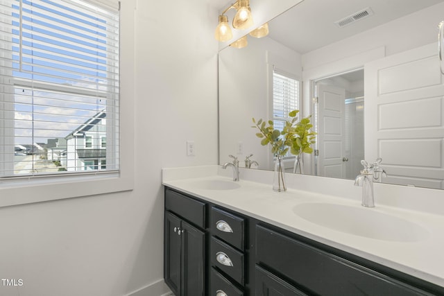 full bath featuring visible vents, a sink, baseboards, and double vanity