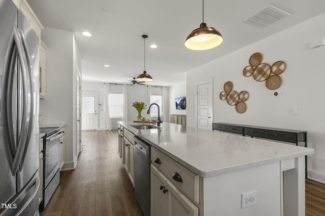 kitchen with stainless steel appliances, dark wood-style flooring, a sink, visible vents, and an island with sink