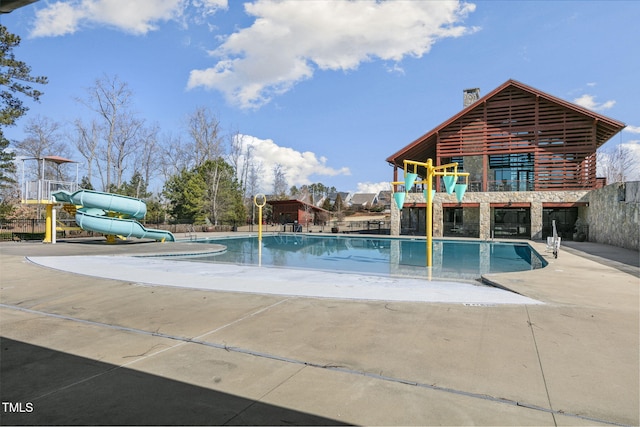 community pool featuring a water slide, a water play area, and fence