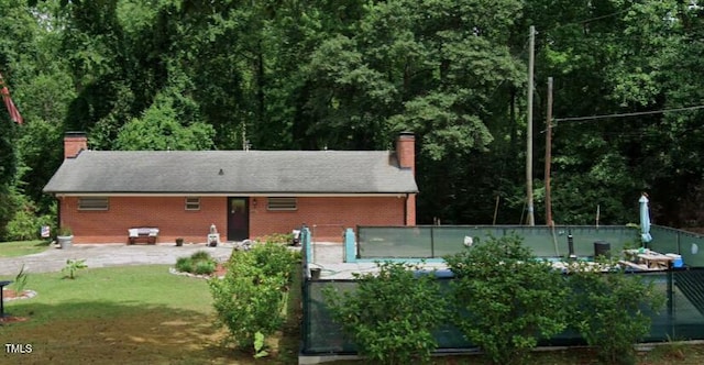 back of house with a chimney, fence, and brick siding