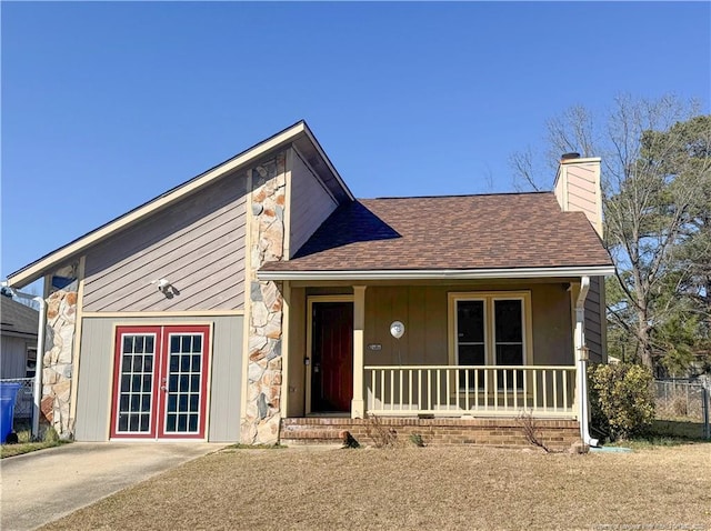 view of front of home featuring stone siding, a porch, french doors, a shingled roof, and a chimney