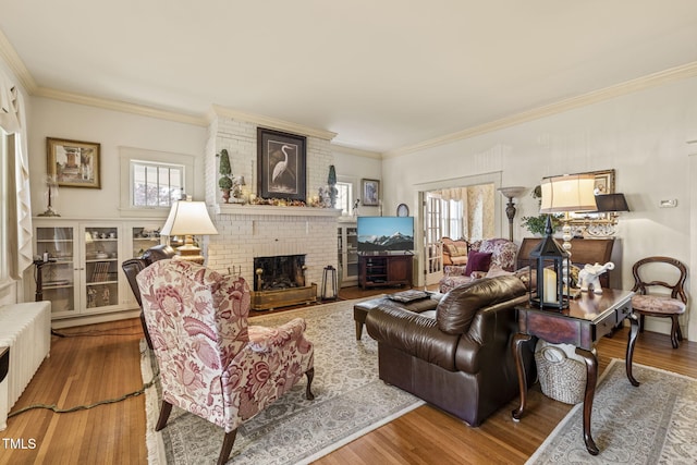 living room with hardwood / wood-style flooring, radiator, a brick fireplace, and a healthy amount of sunlight