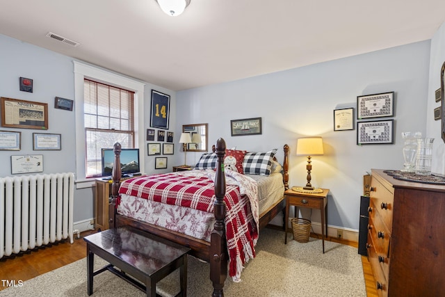 bedroom with radiator and hardwood / wood-style floors