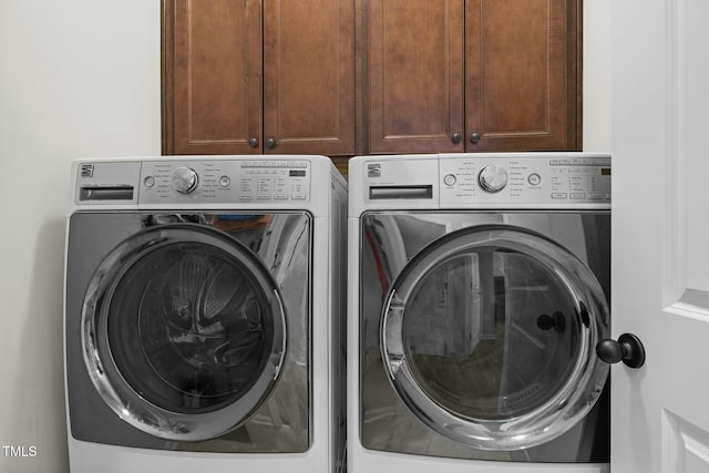 laundry room with separate washer and dryer and cabinets