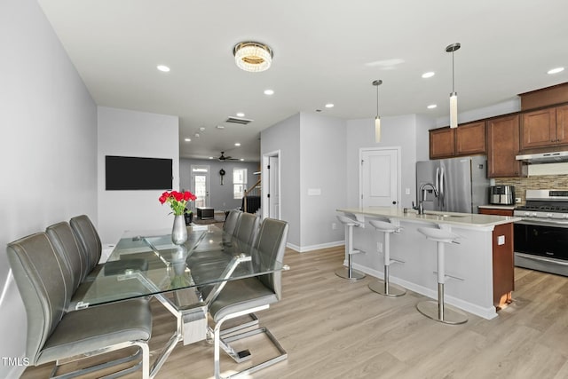 dining space with sink, ceiling fan, and light wood-type flooring