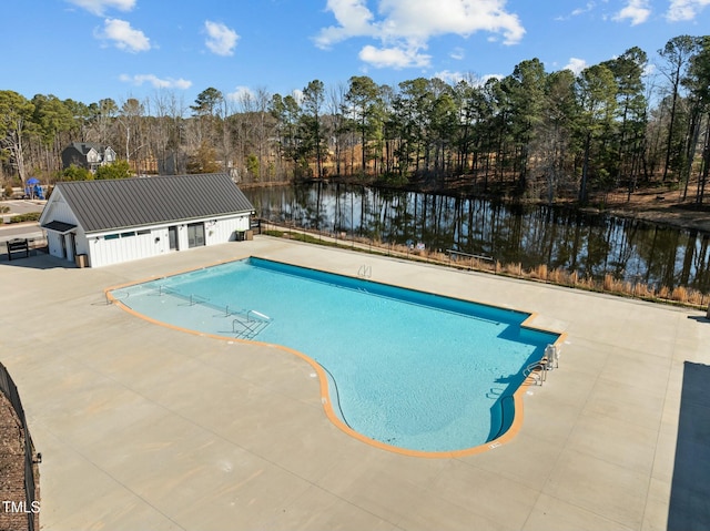 view of pool featuring an outbuilding, a patio, and a water view