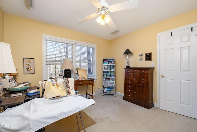 office area featuring a ceiling fan, light colored carpet, visible vents, and baseboards