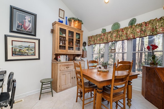 dining area with light tile patterned flooring, baseboards, and vaulted ceiling