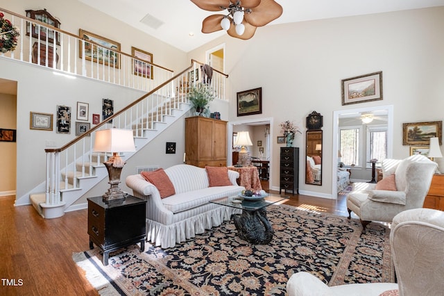 living room with baseboards, a high ceiling, wood finished floors, and stairs