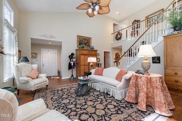 living room featuring high vaulted ceiling, wood finished floors, stairway, baseboards, and ceiling fan