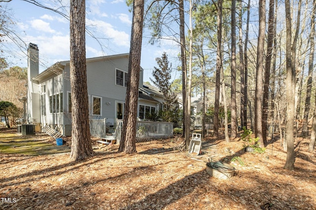 exterior space with central AC, a deck, and a chimney