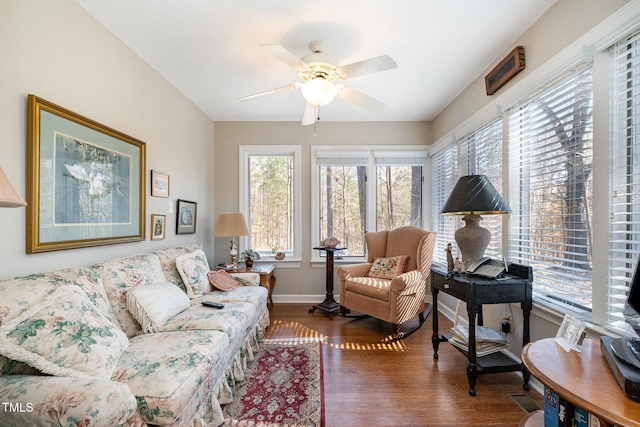 living area with baseboards, ceiling fan, and wood finished floors