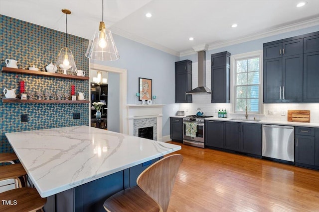 216 N Bloodworth St, Raleigh, NC 27601 - kitchen with light stone countertops, a kitchen breakfast bar, wall chimney range hood, a sink, and stainless steel appliances