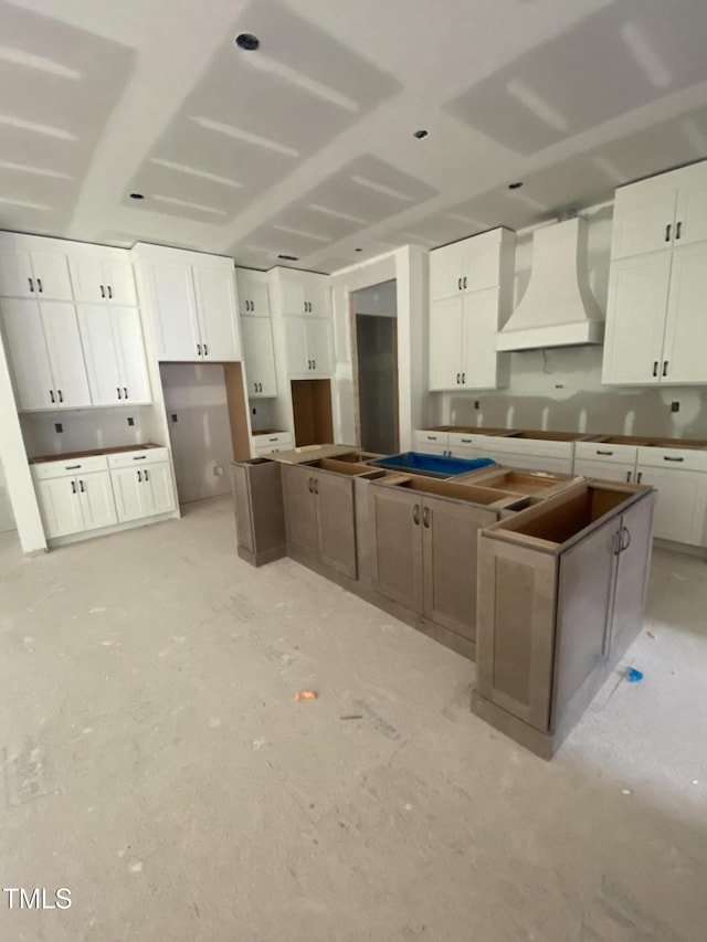 kitchen with a center island, white cabinets, and custom exhaust hood