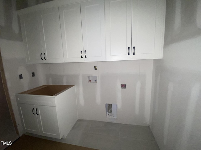 laundry area with dark tile patterned floors, washer hookup, cabinet space, and electric dryer hookup