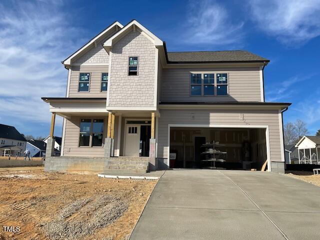 view of front of home featuring concrete driveway, covered porch, and an attached garage