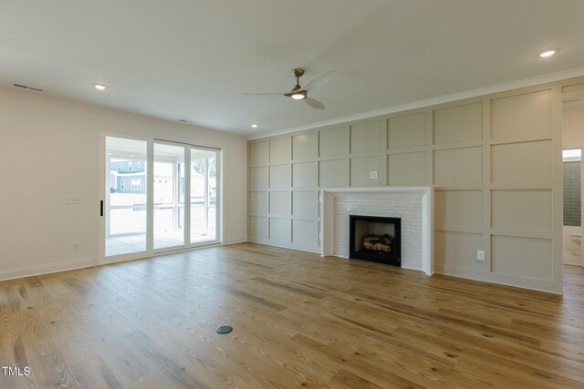 3521 Amelia Grace Dr Lot 67, Fuquay Varina, NC 27526 - unfurnished living room with ceiling fan, crown molding, light wood-type flooring, a fireplace, and a decorative wall