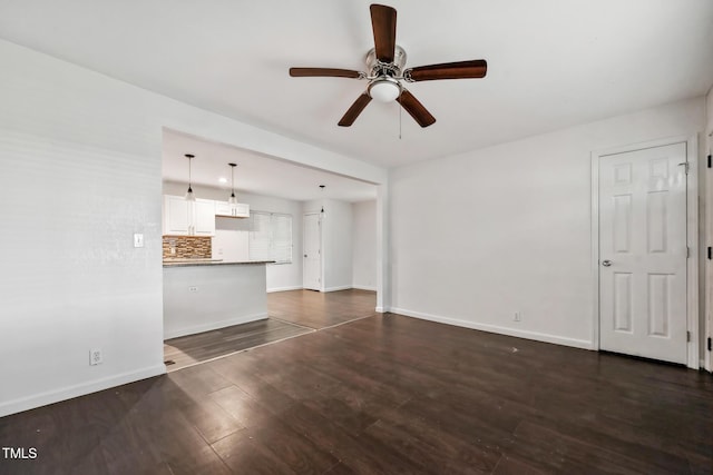 unfurnished living room featuring ceiling fan, dark wood-type flooring, and baseboards