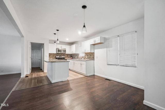 kitchen with stainless steel appliances, white cabinets, decorative backsplash, and light wood finished floors