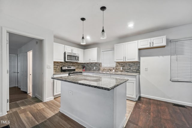 kitchen with appliances with stainless steel finishes, white cabinets, visible vents, and wood finished floors