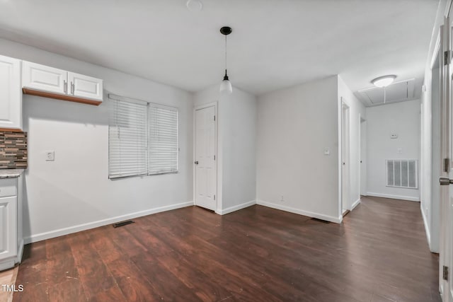 unfurnished dining area featuring attic access, visible vents, baseboards, and dark wood-style floors