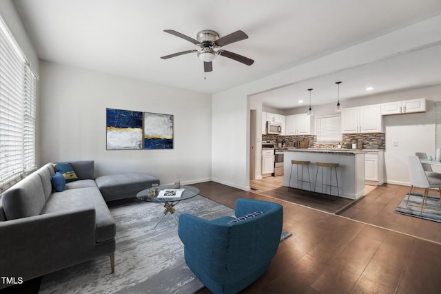 living area featuring baseboards, a ceiling fan, wood finished floors, and recessed lighting