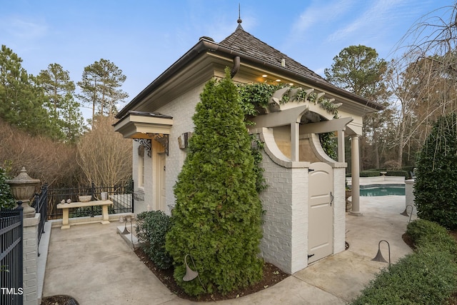 view of side of property featuring fence, a fenced in pool, and brick siding