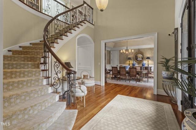 entrance foyer featuring stairway, wood finished floors, baseboards, a high ceiling, and a chandelier