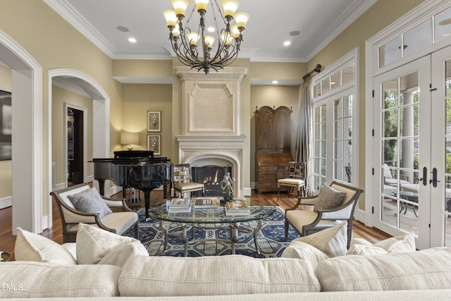 living area with crown molding, french doors, wood finished floors, and a warm lit fireplace