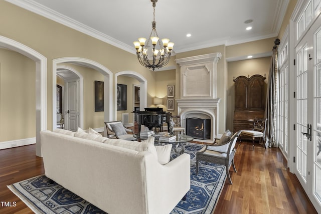 living room featuring baseboards, arched walkways, a warm lit fireplace, ornamental molding, and dark wood-type flooring