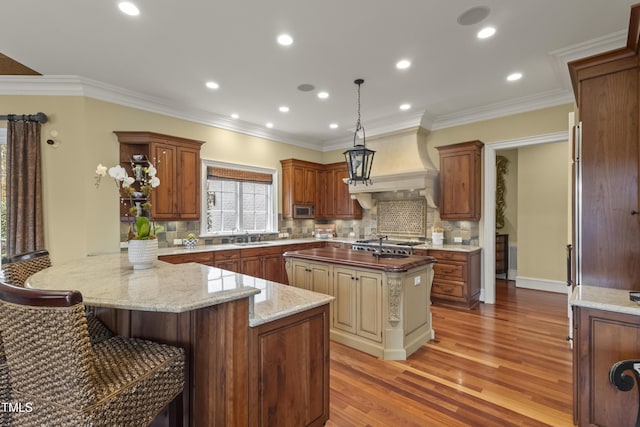 kitchen with custom exhaust hood, a peninsula, crown molding, and light wood finished floors