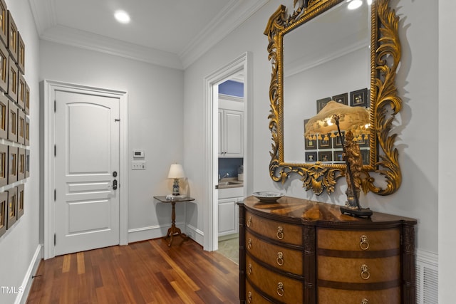 entrance foyer with dark wood finished floors, crown molding, and baseboards