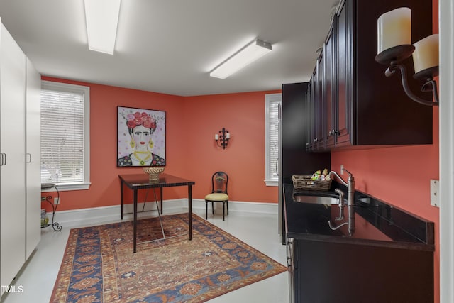 kitchen featuring dark countertops, baseboards, and a sink