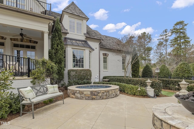 view of patio featuring french doors, a balcony, an outdoor hot tub, and a ceiling fan