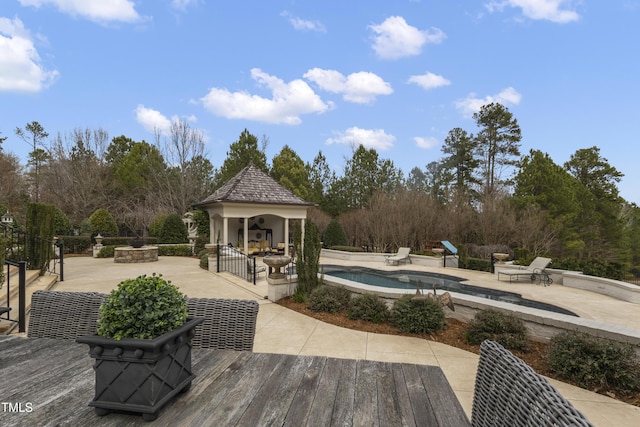 outdoor pool with a gazebo, an outdoor fire pit, and a patio area