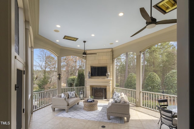 sunroom / solarium featuring a fireplace and a ceiling fan