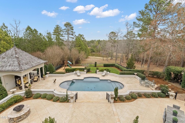 pool with fence, an outdoor fire pit, playground community, a gazebo, and a patio