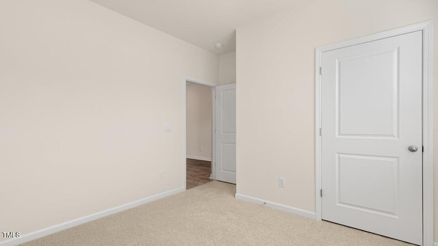 unfurnished bedroom with light colored carpet and baseboards