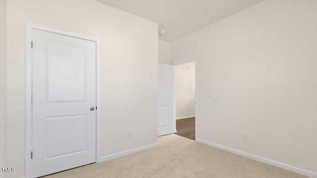 unfurnished bedroom featuring light carpet and baseboards