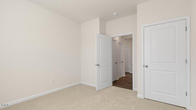 unfurnished bedroom featuring light carpet and baseboards