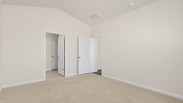 unfurnished bedroom with light carpet, baseboards, visible vents, and vaulted ceiling