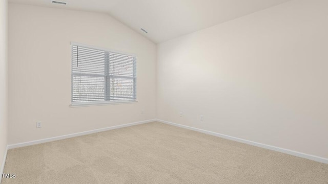 spare room with lofted ceiling, light carpet, visible vents, and baseboards