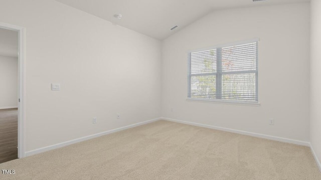 spare room with lofted ceiling, baseboards, and light colored carpet