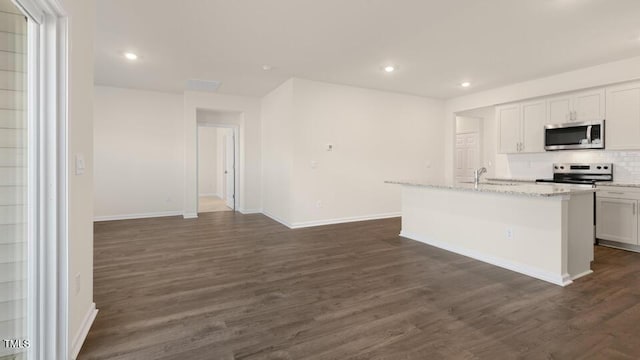 kitchen with dark wood-style flooring, a center island with sink, stainless steel appliances, white cabinetry, and light stone countertops