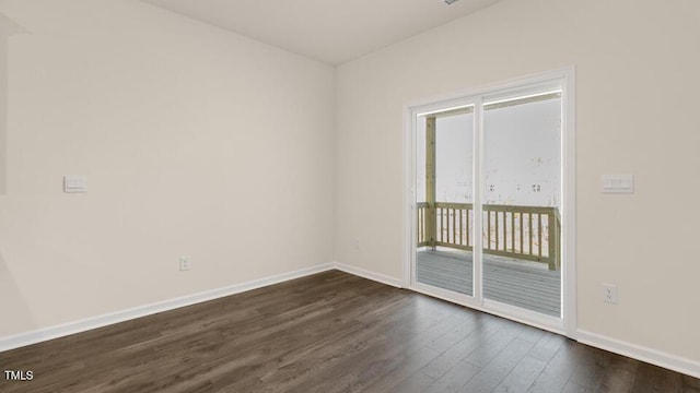 empty room featuring baseboards and dark wood-type flooring