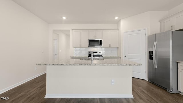 kitchen with stainless steel appliances, white cabinets, and an island with sink