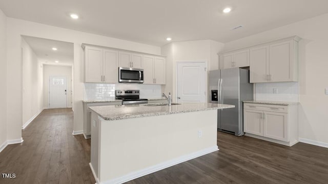 kitchen with stainless steel appliances, white cabinets, a sink, and a center island with sink