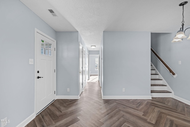 foyer with stairway, visible vents, a textured ceiling, and baseboards